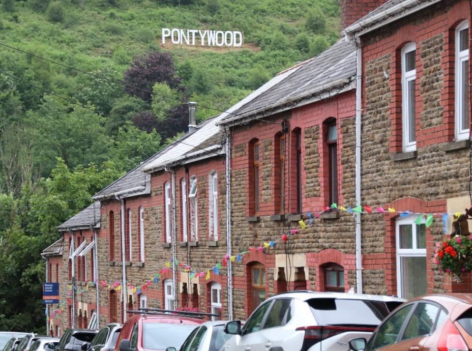 Row of terraced houses in south wales vally with Pontywood sign on hillside above