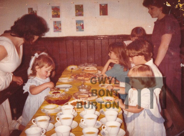 Children eating cakes and many cups of tea